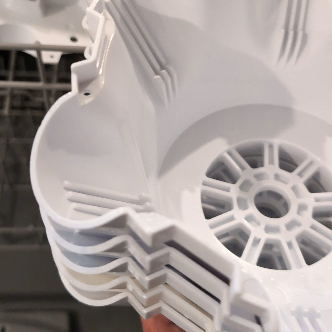 A stack of white plastic grow trays, likely filters or mesh screens, held by a hand