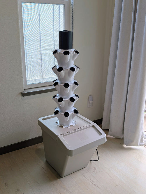 V-Gro tower with 5 trays set up on top of a Ikea storage box, indoors beside a window
